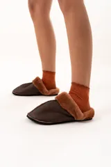 Pantuflas de cuero color chocolate con interior de piel sintética al tono y suela plana.