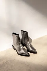 Bota corta de cuero metalizado en tono plateado con efecto arrugado, de caña media, punta fina y taco bajo cuadrado.