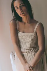 Vestido midi semitransparente de viscosa con escote recto y tirantes finos. Presenta bordados florales a contraste en el pecho y detalle de lazadas ajustables en los laterales.