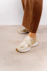 Zapatillas deportivas color blanco con detalles en beige y suela marrón.