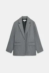 Blazer de paño gris con cuello solapa, manga larga y cierre frontal con un botón. Cuenta con bolsillos delanteros con solapa.