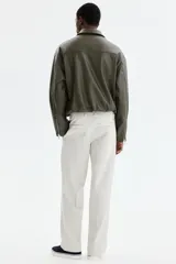 Pantalón sastrero de corte relajado en sarga color beige, con cierre y botón, bolsillos laterales y bolsillos traseros con botón oculto. Presenta piernas con pliegues.