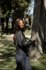 Blusa blanca de lino con mangas largas abullonadas, escote en V con lazo de ajuste frontal y detalles de puntilla en los bordes.