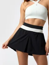 Falda pantalón deportiva de color negro con pretina ancha tejida en franjas blanca y negra, diseño plisado al frente y shorts internos.