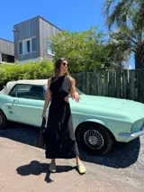 Vestido midi negro con cuello halter y aberturas laterales en la cintura.