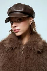 Boina estilo cap con visera, confeccionada en cuero vegano de color marrón con acabado texturizado.