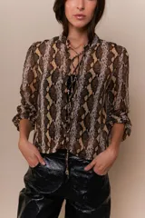 Blusa roja con estampado de piel de serpiente, escote en V con cordones y mangas 3/4 con puños elásticos.