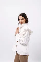 Campera de pana color blanco, de corte oversize, con cuello alto, cierre frontal de botones y volados decorativos en los hombros y cuello.