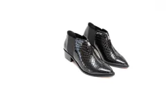Botin de cuero negro con acabado charol y textura de reptil. Presenta cierre frontal con cremallera, paneles laterales elásticos y tacón bajo de bloque.