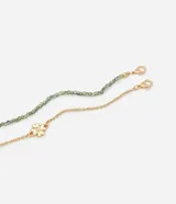 Kit de dos pulseras, una de cadena metálica dorada con dije de trébol y otra compuesta por cristales facetados en tono verde.