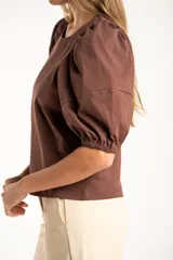 Remera de algodón negro con mangas cortas abullonadas, cuello redondo y costura central frontal.