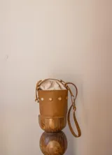 Cartera tipo canasta de cuero con estampado animal print de vaca en blanco y negro. Tiene correa larga de cuero negra y herrajes metálicos plateados.