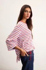 Remerón de algodón a rayas horizontales celestes y rojas, con silueta oversize, cuello redondo y mangas 3/4.