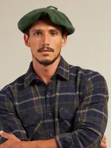 Boina azul marino de paño con visera pequeña y botón decorativo en la parte superior.