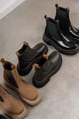 Botas tipo Chelsea de cuero color marrón con paneles elásticos laterales negros y suela track de goma negra con plataforma.