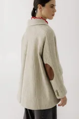 Blazer de corte recto y holgado en color beige con textura de espiga. Presenta solapas clásicas, cierre frontal con un botón central y bolsillos laterales con solapa.