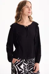 Blusa negra de viscosa con cuello redondo, lazo ajustable en el escote y volados decorativos en los hombros.