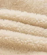 Campera de fleece color beige con diseño de paneles, costuras expuestas en color negro y cierre frontal. Posee cuello alto, mangas largas con puños elásticos y forro interior.