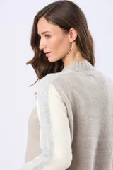 Buzo tejido de punto con cuello redondo y mangas largas. Presenta un diseño de bloques de color con franjas en tonos contrastantes a lo largo de las mangas y un detalle de etiqueta de cuero en el ruedo.