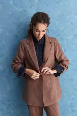 Blazer de corte sastrero con silueta relajada, solapas tradicionales, cierre frontal de un botón y bolsillos de vivo.