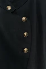 Blazer de Zara Woman Collection confeccionado en mezcla de lino y algodón, en color negro. Presenta cuello subido, cierre frontal cruzado con botones dorados, mangas largas con puños acampanados terminados en volante y forro interior a contraste con rayas verticales.