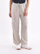 Pantalón cargo color verde claro, de corte recto y tiro alto, con cintura elástica ajustable con cordón, bolsillos laterales tipo cargo con solapa y ajuste elástico en los tobillos.