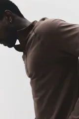 Remera deportiva de manga larga con cuello elevado y medio cierre, de color marrón, con diseño entallado Muscle Fit y detalles de paneles texturizados.