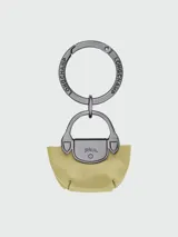 Llavero Longchamp modelo Le Pliage Xtra, con diseño de mini cartera en cuero color amarillo pálido y herrajes metálicos oscuros con el logo de la marca grabado.