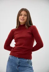 Polera de tejido de punto fino, color bordó, con cuello alto y terminaciones con borde ondulado en cuello y ruedo. De manga larga y ajuste al cuerpo.