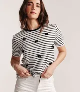 Blusa de media malla a rayas horizontales blancas y negras, con cuello redondo y mangas cortas. Aplicación de moñas negras.