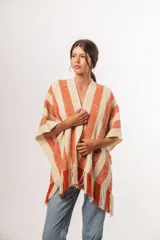 Ruana tejida a mano en Uruguay, con lana merino color crudo y franjas verticales color terracota.