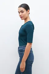 Remera verde de tejido canalé con cuello redondo y media manga. Tiene una abertura frontal con botones.
