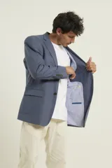 Saco azul de lino con dos botones, solapa de muesca, dos bolsillos delanteros con solapa y un bolsillo en el pecho.