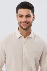 Camisa de lino a rayas finas en tonos beige y blanco, de manga larga con puños vueltos, cuello camisero y cierre frontal de botones. Cuenta con un pequeño logo bordado en el pecho.