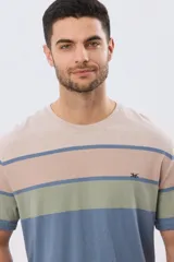 Remera de manga corta y cuello redondo, con diseño de bloques de color y franjas horizontales en tonos azul, celeste y gris, con pequeño logo bordado en el pecho.