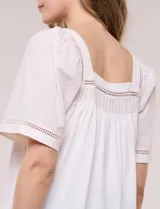 Blusa de corte holgado color marfil, confeccionada en mezcla de modal y algodón, con escote cuadrado y mangas cortas adornadas con detalles de puntilla calada.