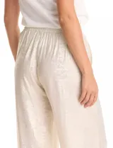Pantalón wide leg de tela laminada metalizada color blanco, con pretina elástica y lazo de ajuste en la cintura. Cuenta con bolsillos laterales.