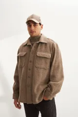 Camisa estilo leñadora marrón con diseño de espiga, cuello clásico, abrochadura frontal a la vista, bolsillos plaqué con tapa en el pecho, mangas largas con puño y botón.