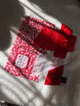 Campera de estilo collage confeccionada con una mezcla de telas en tonos rojos, incluyendo estampados florales, encaje y detalles bordados. Presenta un diseño artesanal único con texturas variadas.