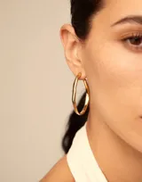 Aros de tipo argolla abiertos con diseño minimalista e irregular, bañados en oro y con cierre de tuerca.
