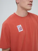 Remera de manga corta color beige, con cuello redondo y diseño holgado. Cuenta con un pequeño estampado rectangular en el pecho con motivo futbolero.