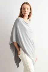 Capa tejida en hilo de lurex color beige, con cuello bote y diseño asimétrico de corte fluido.