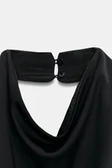 Top negro sin mangas con cuello halter drapeado y cierre posterior con botón.