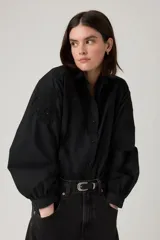 Camisa negra de manga larga con detalles bordados y calados en los hombros y el pecho. Presenta cuello clásico y cierre frontal con botones.