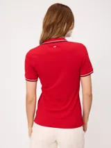 Remera polo azul marino de manga corta, con cuello en V sin botones y ribetes tricolores en el cuello y los puños.