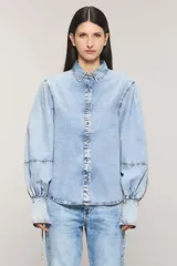 Camisa de denim celeste con calce regular, cuello camisero, cierre frontal con botones metálicos y mangas estilo balloon con puños largos ajustables.