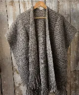 Ruana abierta de lana merino, color gris, de tejido texturizado con flecos en el borde inferior.