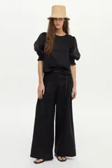 Pantalón de lino color beige, de pierna amplia, con elástico en la cintura, pinzas en el frente y bolsillos laterales y traseros.