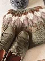 Sweater tejido a mano con diseño de canesú circular en tonos verde, marrón, beige y blanco. Presenta una textura suave y abrigada, con cuello redondo y puños acanalados.
