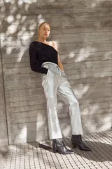 Pantalón babucha plateado de cuero de oveja italiano impermeabilizado, con cintura elastizada, bolsillos laterales y tobillo recto. Incluye cintas del mismo cuero para fruncir el puño del tobillo.